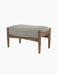 A studio shot of The Seal Ottoman, showing its oiled walnut frame and light grey Re-Wool 218 upholstered cushion.