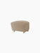 The Tired Man Ottoman in a beige textile with natural oak legs and brass casters, shown from an angle on a black background.