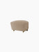 The Tired Man Ottoman in beige textile with dark wood legs and front brass casters, pictured on a black background.