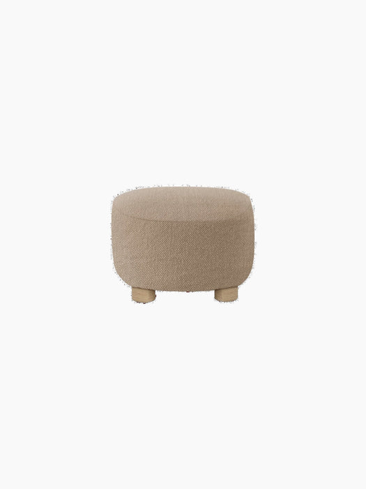 Back view of The Tired Man Ottoman, upholstered in a textured, light brown textile with four short, natural oak legs.
