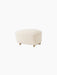 An angled view of The Tired Man Ottoman, upholstered in an off-white, textured Logan Flint fabric on a black background.