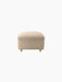 Front view of The Tired Man Ottoman upholstered in a light, textured textile, with natural oak legs and front brass casters.