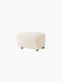 The Tired Man Ottoman in cream bouclé fabric, shown at an angle. It has dark wood legs with two brass casters at the front.