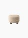 Back view of The Tired Man Ottoman, upholstered in a cream textured textile, showing its rounded shape and dark wooden legs.