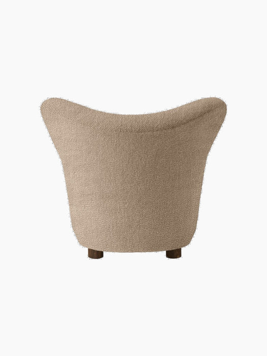 Back view of The Tired Man Lounge Chair upholstered in a textured beige textile, showing its curved back and dark oak legs.