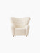 Front view of The Tired Man Lounge Chair in cream textile with a high, curved back, rounded arms and brass castors.