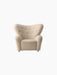The Tired Man Lounge Chair, upholstered in a light, textured fabric with a tufted winged back and brass castors.
