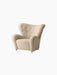 The Tired Man Lounge Chair upholstered in a cream textile, featuring a high curved back, tufted details, and gold castors.