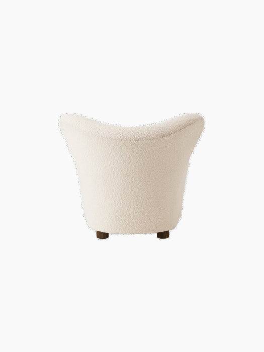 Back view of The Tired Man Lounge Chair. The chair has a high, curved back and is upholstered in a cream textured fabric.