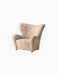 Angled view of The Tired Man Lounge Chair in plush, cream-coloured textile with a high, tufted back & brass front castors.