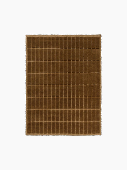 Top-down view of a square, brown rug featuring a plush, tufted grid pattern of vertical rectangles and a simple woven border.
