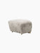 A Tired Man Ottoman footstool upholstered in light green Green Tea sheepskin, shown at an angle on a plain black background.
