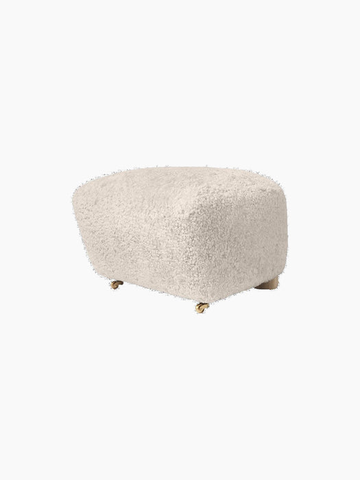 The Tired Man Ottoman in soft, off-white Moonlight sheepskin. The plush footstool features oak legs with brass castors.