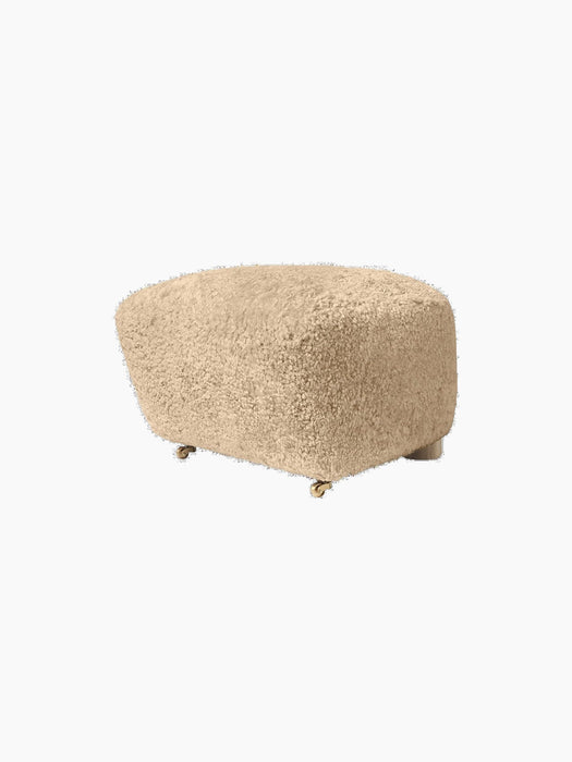 The Tired Man Ottoman upholstered in plush honey sheepskin. A rounded footstool with small brass castors on the front.