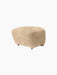 The Tired Man Ottoman upholstered in plush honey sheepskin. A rounded footstool with small brass castors on the front.