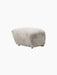 Three-quarter view of The Tired Man Ottoman in plush Green Tea Sheepskin, highlighting its soft texture on a black background