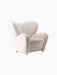 The Tired Man Lounge Chair, upholstered in off-white sheepskin, shown from a three-quarter angle against a black background.