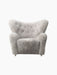 Front view of the plush Tired Man Lounge Chair upholstered in Green Tea sheepskin, featuring a curved, buttoned backrest.