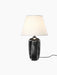 Torso Table Lamp, 57 with a glossy black ceramic base and an off-white linen shade, illuminated against a black background.