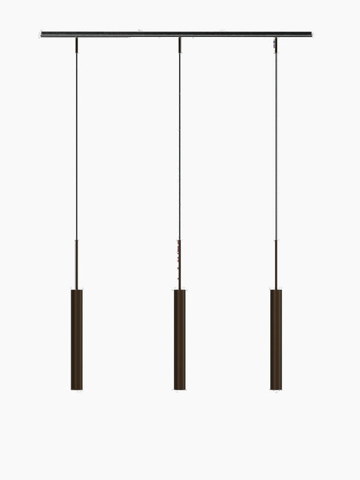 A front-on studio shot of the Tubulaire Rail Pendant with three reeded, bronzed brass lights against a stark black background