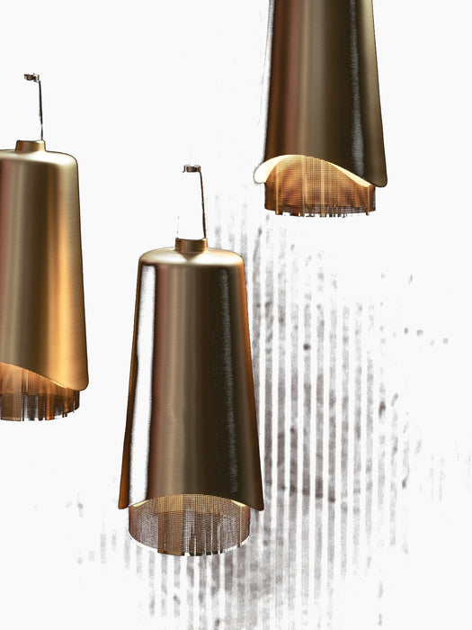 A close-up of three brass Umanoff Pendants hanging at different levels against a dark, ribbed wall, emitting a warm glow.