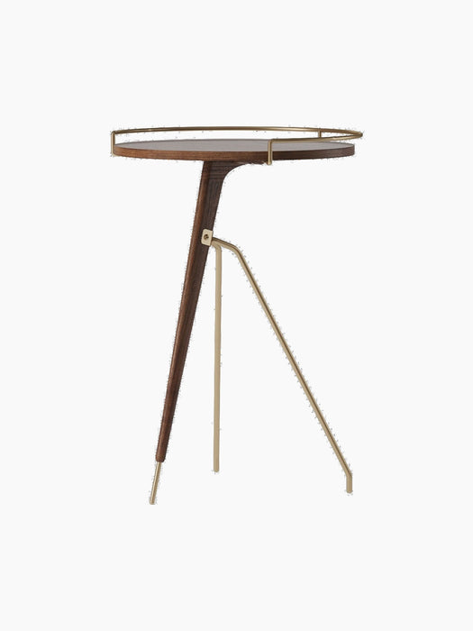 The Umanoff Side Table in dark walnut and brushed brass, shown from an angle. Tall version with a tripod base and round top.
