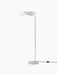 A switched-on Wing Floor Lamp in polished aluminium. It has a slender stem, a round base, and a rotating wing-shaped shade.