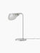 A tilted, side-angle view of the Wing Table Lamp in polished aluminium, showing its round base and wing-shaped shade.