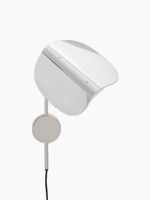 Side view of the Wing Wall Lamp in polished aluminium. The wing-shaped shade is tilted downwards, emitting a warm glow.
