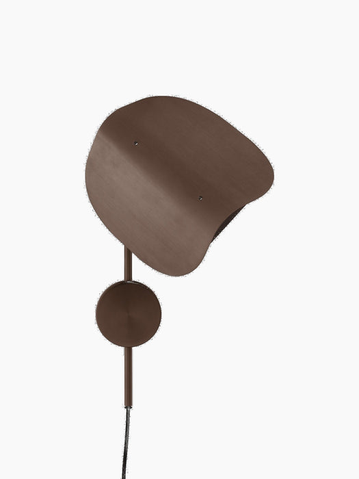 The Wing Wall Lamp in bronzed aluminium, turned off against a black background. It has a distinctive wing-shaped shade.
