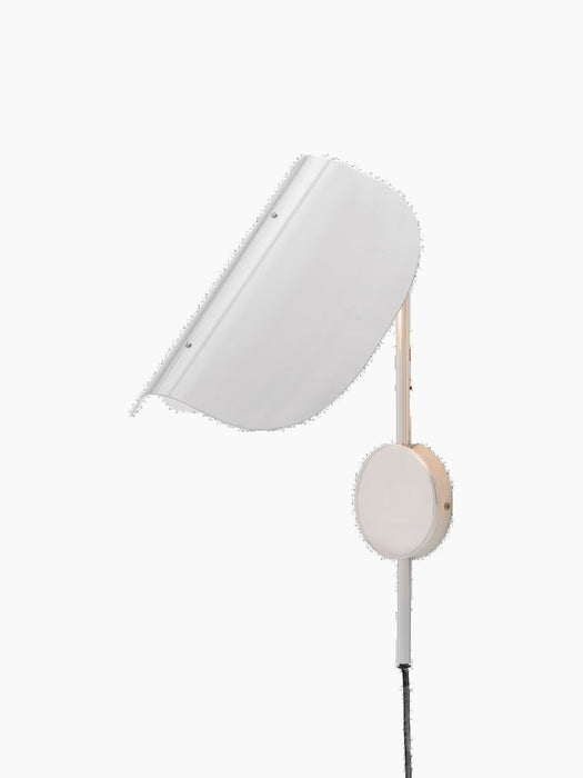 A polished aluminium Wing Wall Lamp, seen from an angle. The light is on, illuminating its distinct, folded wing-like shade.