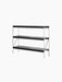 Angled view of the Zet Storage System, featuring three wide black oak shelves supported by a minimalist ivory steel frame.